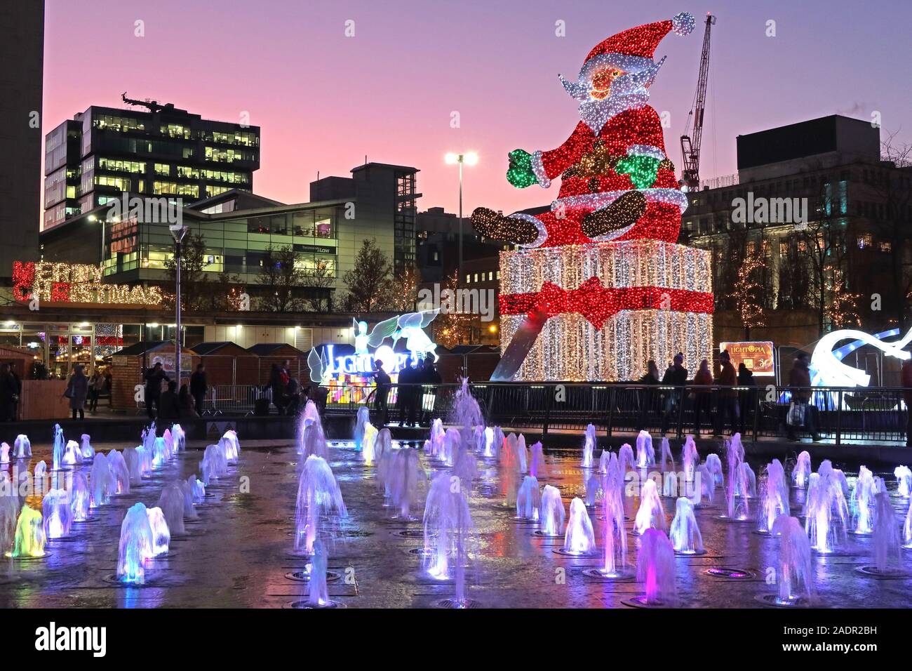 Merry Christmas, aus Piccadilly Gardens, Manchester, England, Großbritannien, M1 1RN Uhr - Weihnachtsmann in der Abenddämmerung Stockfoto