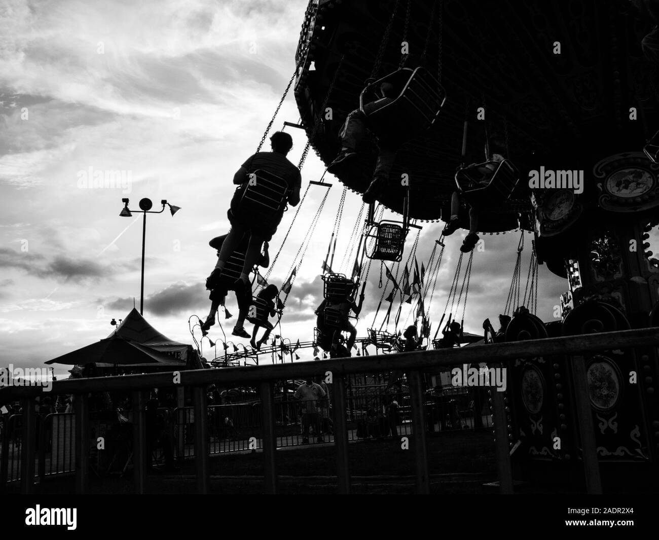 Silhouette gegen einen hellen Himmel fallen Menschen eine Fahrt an der County Fair genießen. Stockfoto