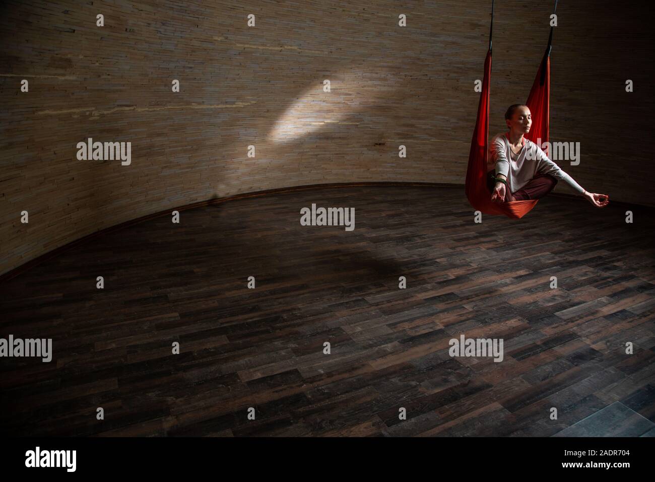 Geräumige Zimmer und Frau Meditation in orange Hängematte Stockfoto