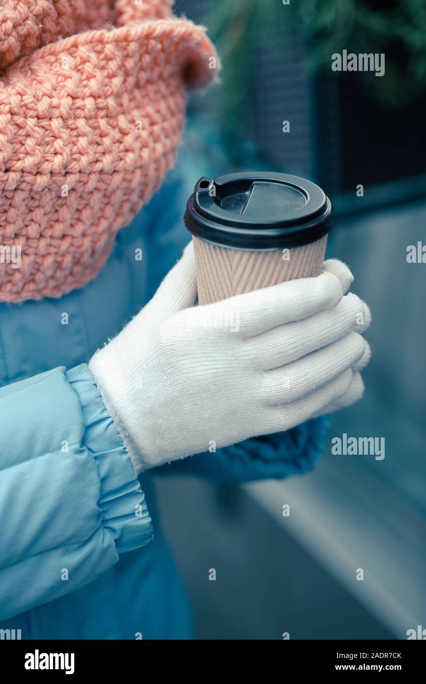 Hände in warme Handschuhe holding Karton Tasse Kaffee Stockfoto