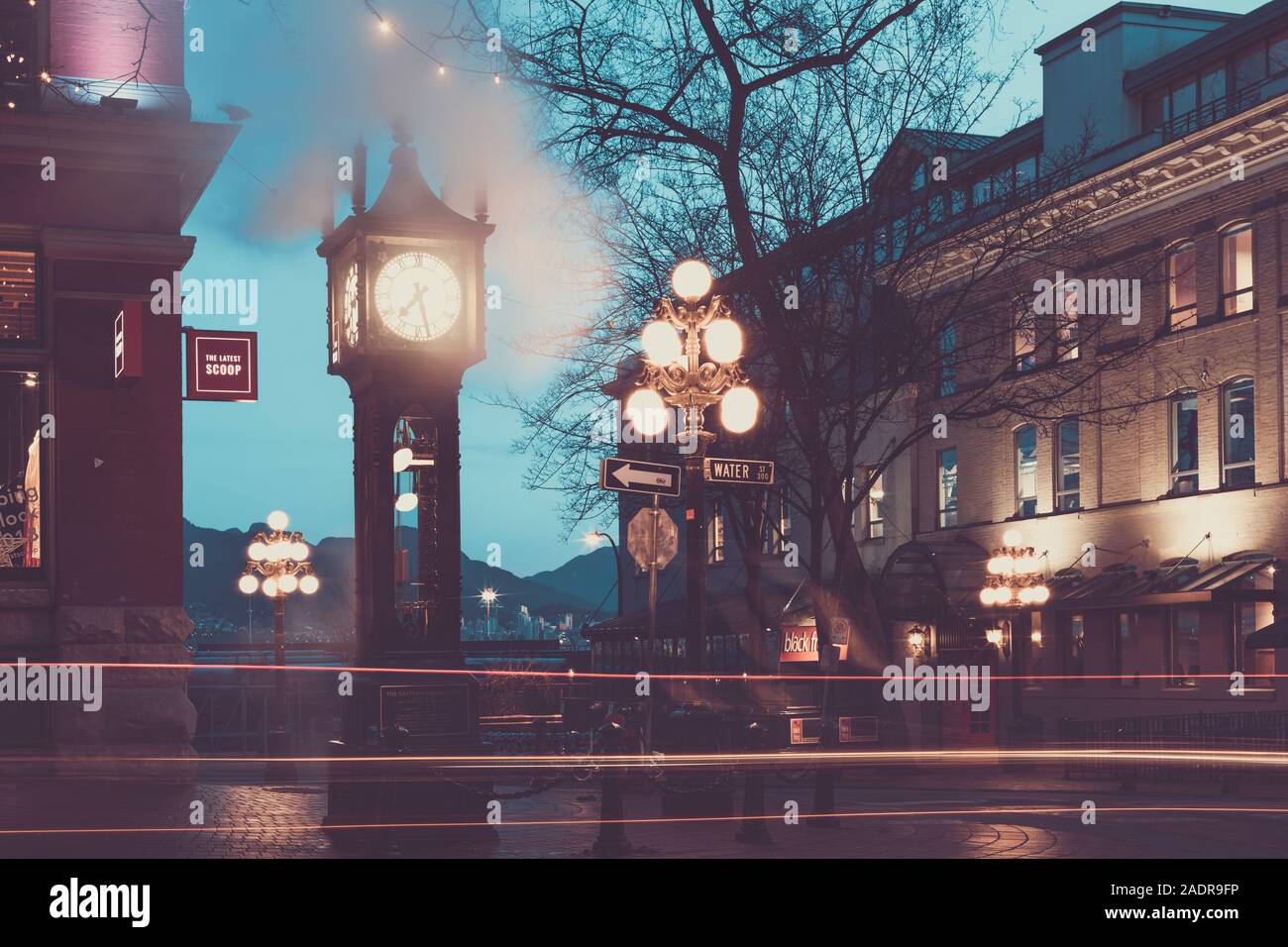 Vancouver, British Columbia - Dez 3, 2019: Der berühmte Steam Clock in Gastown in Vancouver city mit Autos leichte Wanderwege in der Nacht Stockfoto