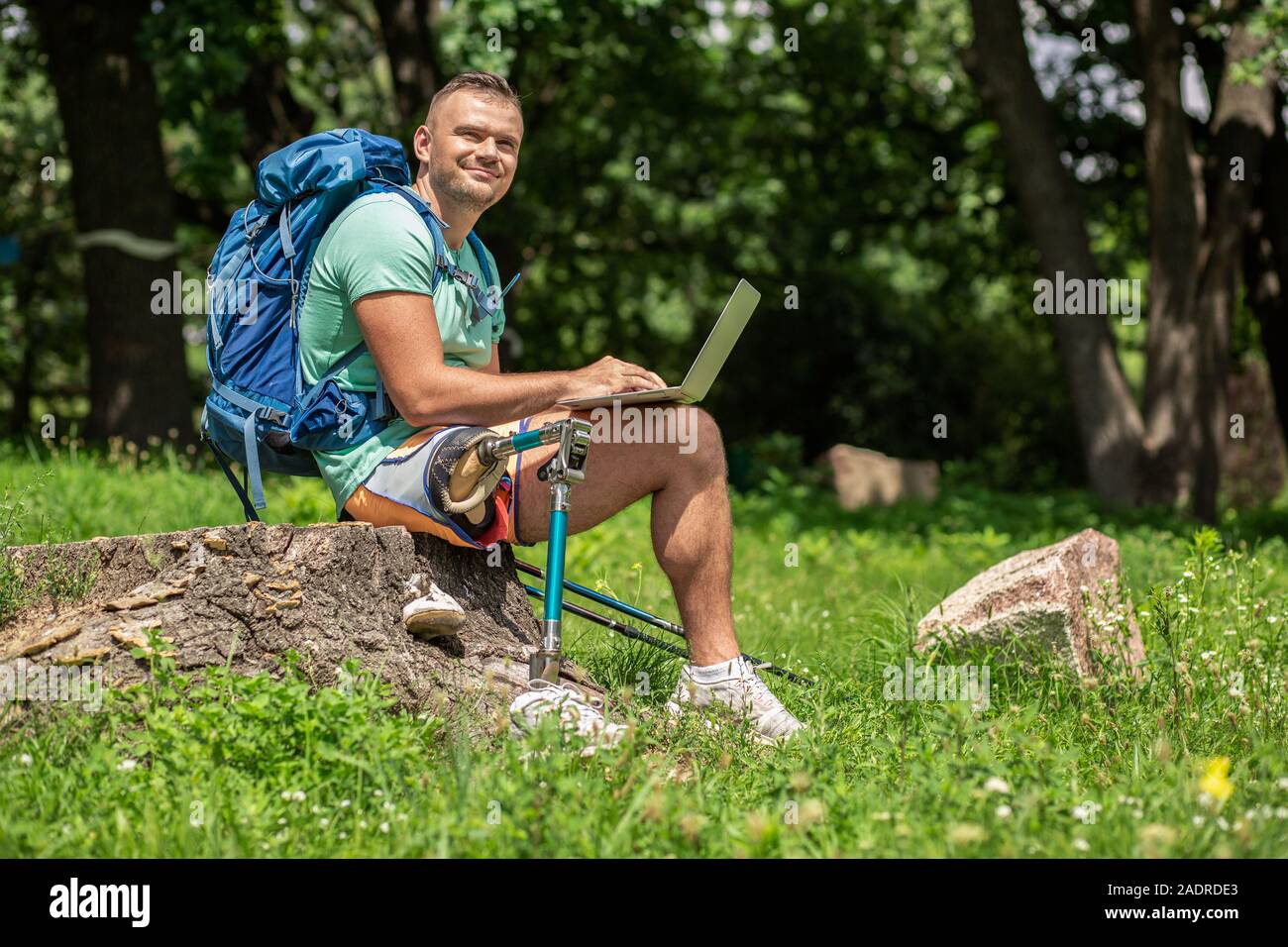 Freudiger Mann mit Prothese mit Laptop im Freien Stockfoto