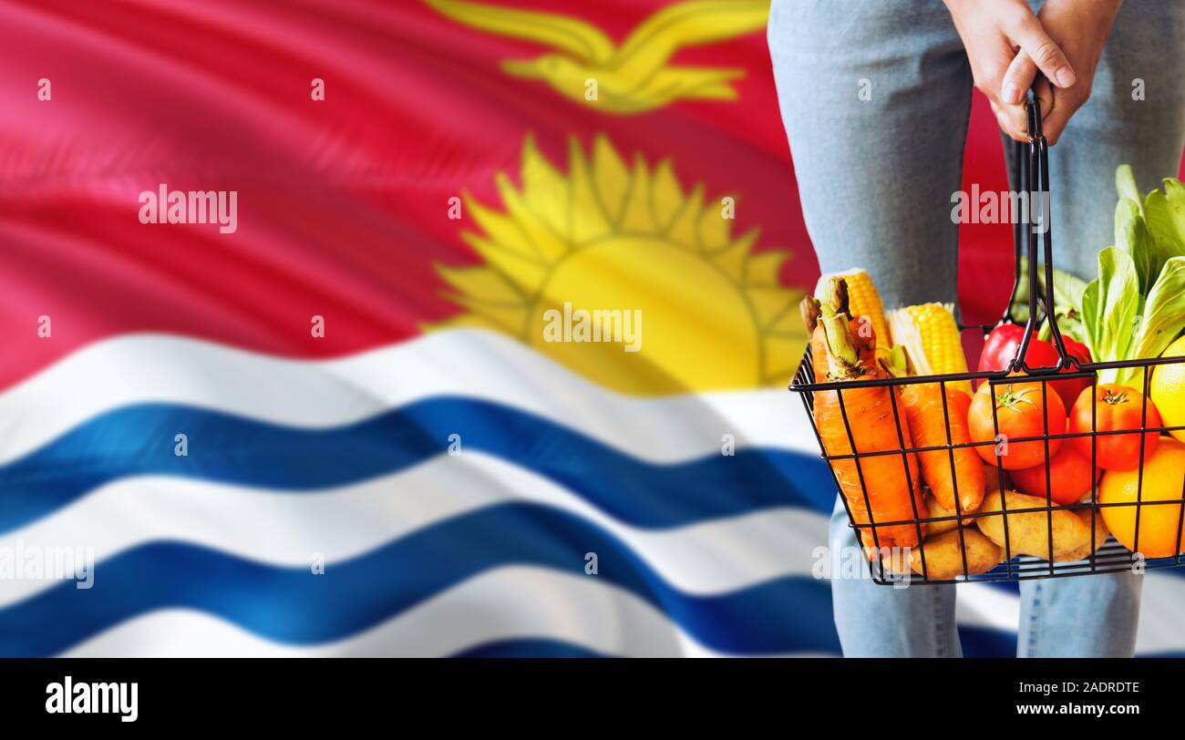 Frau hält Supermarkt Korb, Kiribati wehende Flagge Hintergrund. Wirtschaft Konzept für frisches Obst und Gemüse. Stockfoto