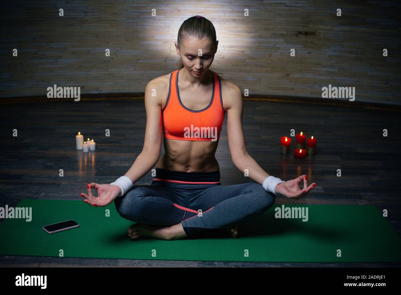 Junge Frau sitzend, die Beine gekreuzt und meditieren Stockfoto