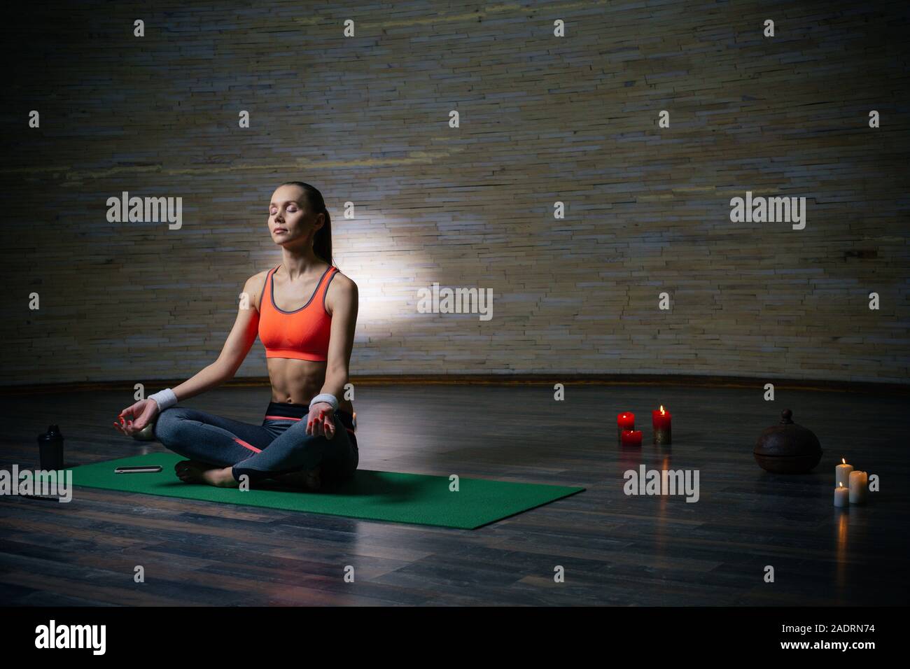 Die ganze Länge der Frau im leeren Raum meditieren auf Yoga Matte Stockfoto