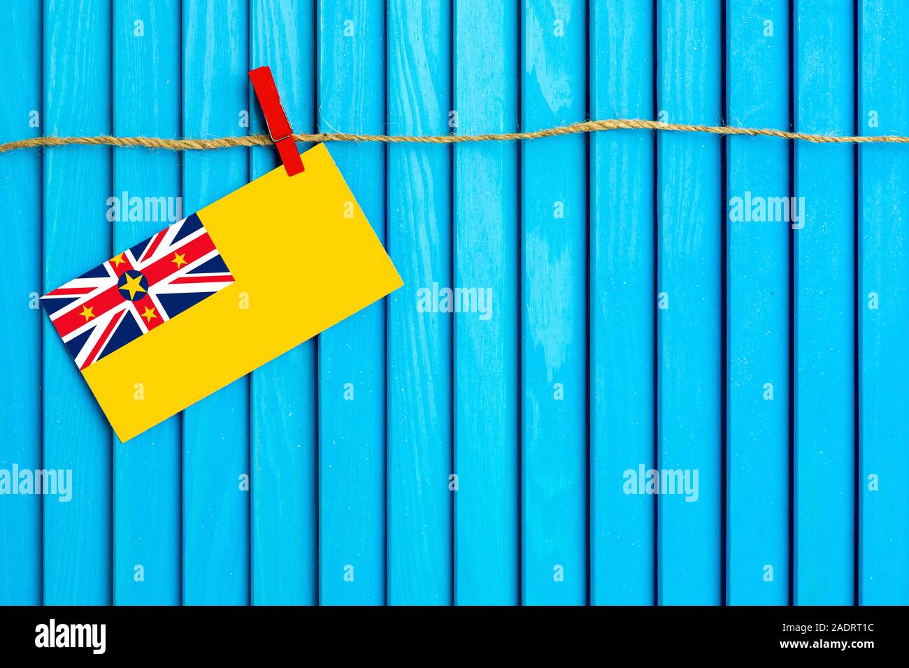 Flagge von Niue hängen auf Wäscheleine mit Holz Wäscheklammern auf aqua blau Holz- Hintergrund geklebt. Nationalen Tag Konzept. Stockfoto