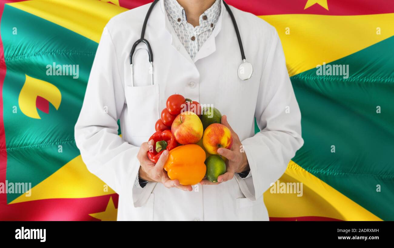 Arzt hält Sie Obst und Gemüse in die Hände mit Grenada Flagge Hintergrund. Nationalen Gesundheitswesen Konzept, medizinische Thema. Stockfoto