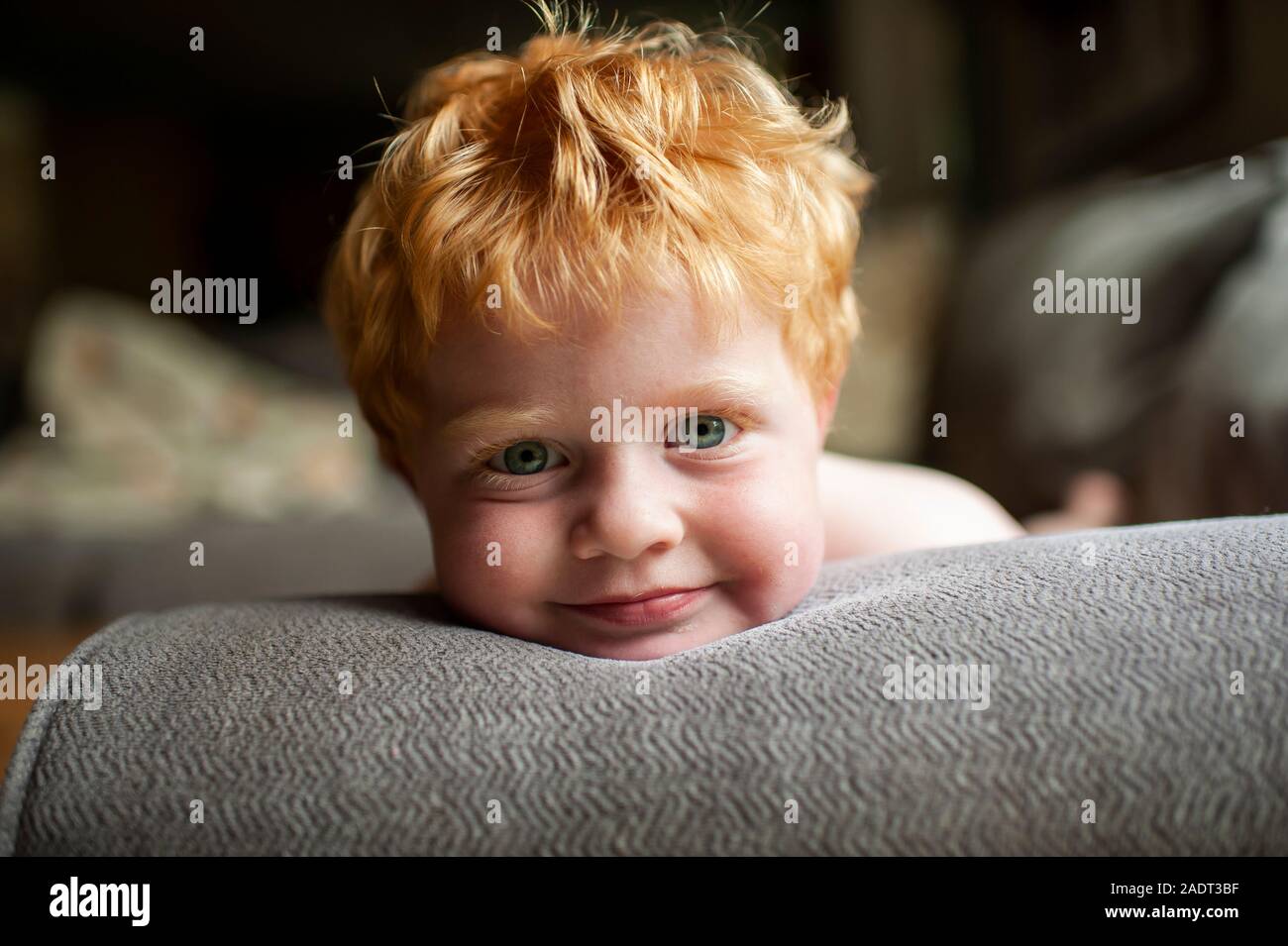 Portrait von Kleinkind Junge mit roten Haaren Festlegung auf der Couch zu Hause lächeln Stockfoto