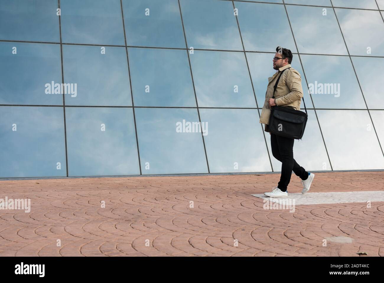 Geschäftsmann ist Laufen mit einem verglasten Gebäude in der Rückseite Stockfoto