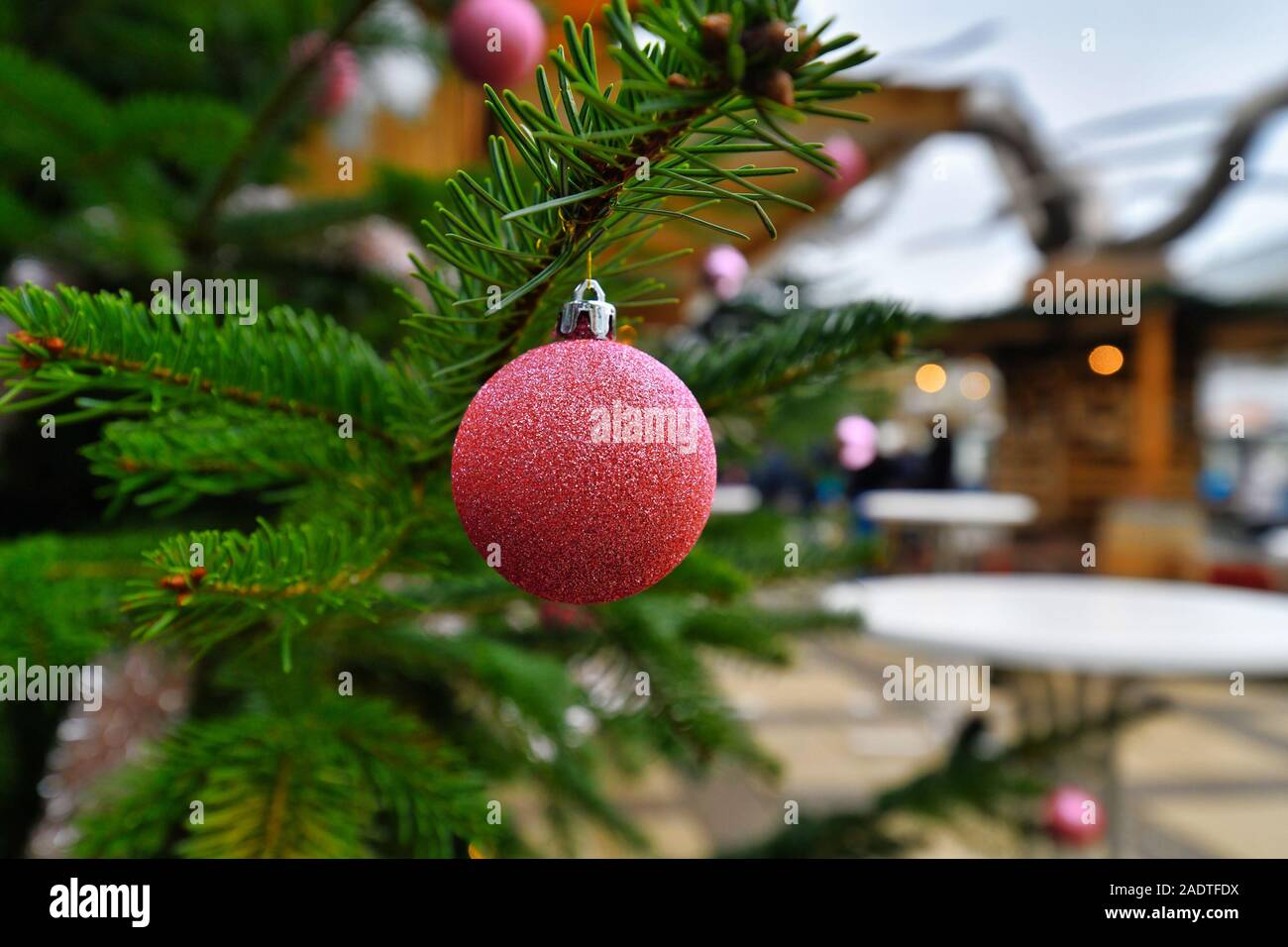 Funkelnden hell rosa Christbaumschmuck Christbaumkugel mit Verkaufsstand in verschwommenen Hintergrund auf den traditionellen Weihnachtsmarkt Stockfoto