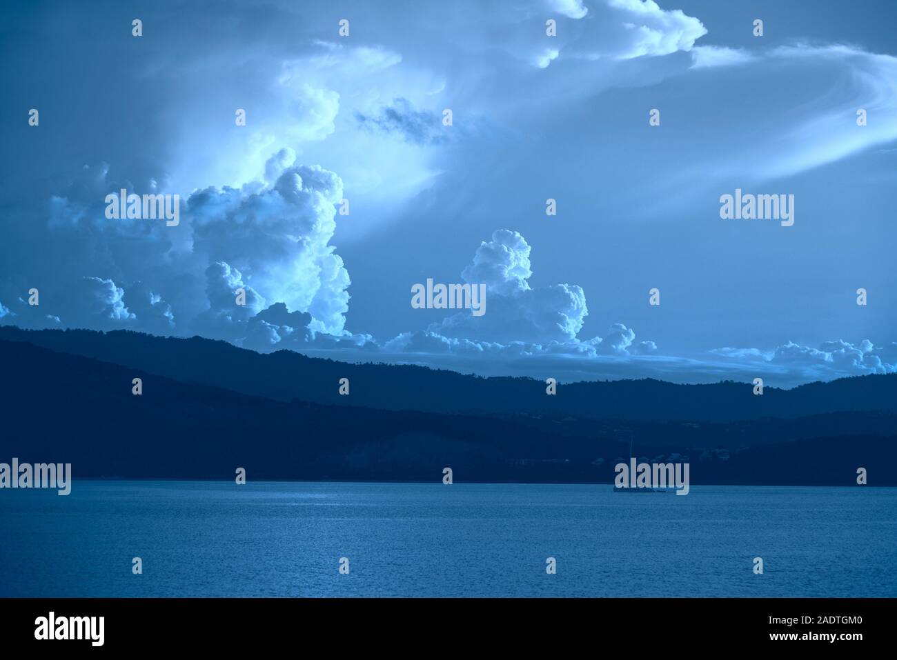 Seashore Ansicht mit tropischen Wald und flauschige Wolken Farben in Blau. Stockfoto