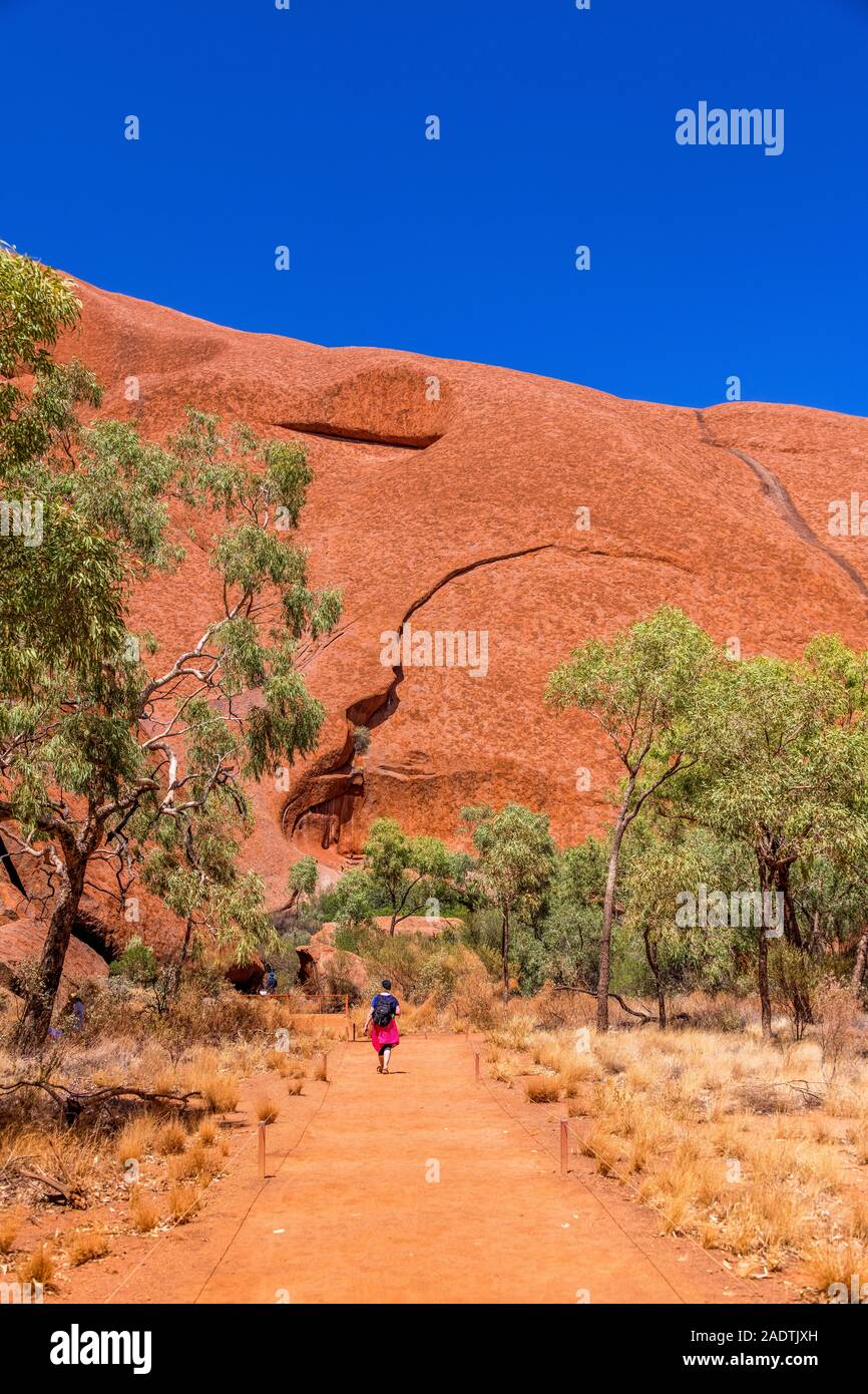 Ein Spaziergänger entlang der Mala-Wanderung, die dem Rundkurs um den Fuß des Uluru (Ayres Rock) folgt. Uluru, Northern Territory, Australien Stockfoto