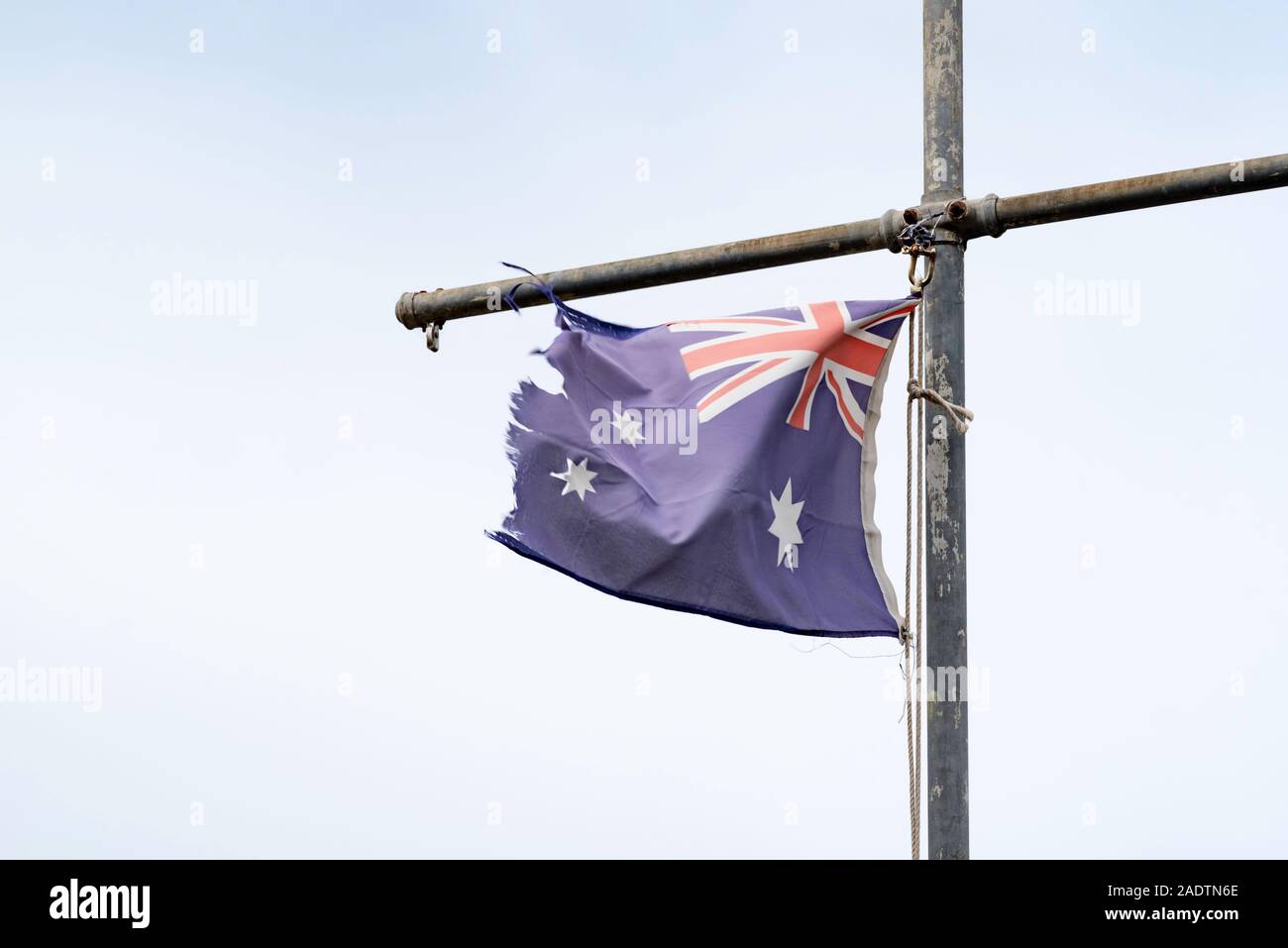 Einer zerrissenen und zerfetzten australischen Blue Ensign Flagge von einem Behelfsmäßigen flag Pole in Sydney, Australien, hängend Stockfoto