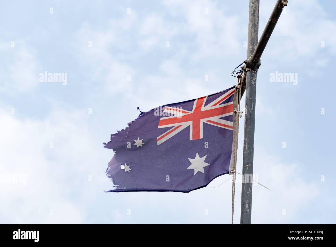 Einer zerrissenen und zerfetzten australischen Blue Ensign Flagge von einem Behelfsmäßigen flag Pole in Sydney, Australien, hängend Stockfoto