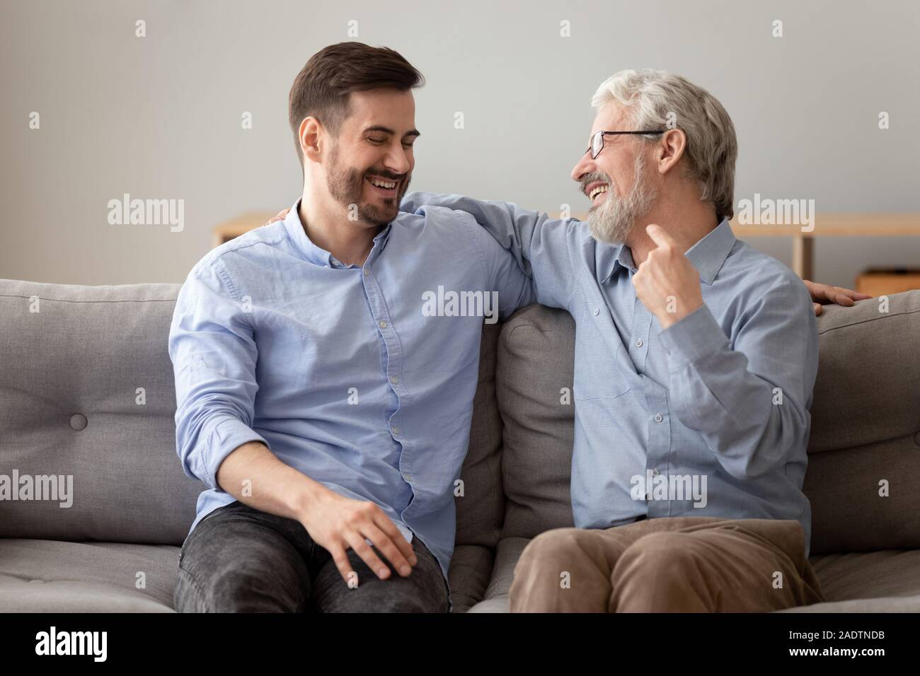Alter Vater erwachsener Sohn, lachen, Spaß haben, sitzen auf dem Sofa Stockfoto