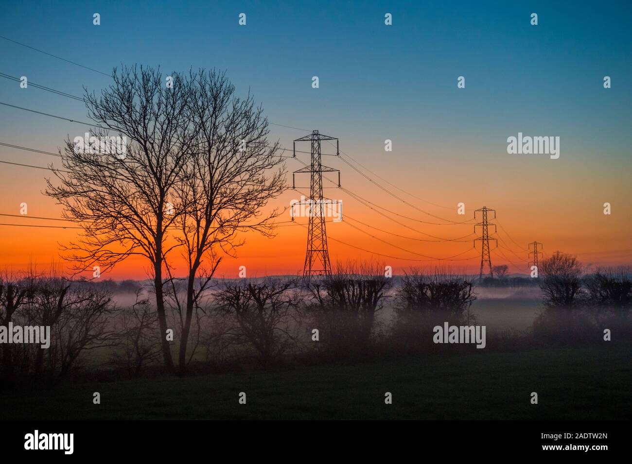 Strommasten bei Sonnenuntergang auf der Somerset Levels Dec 4 2019 Stockfoto