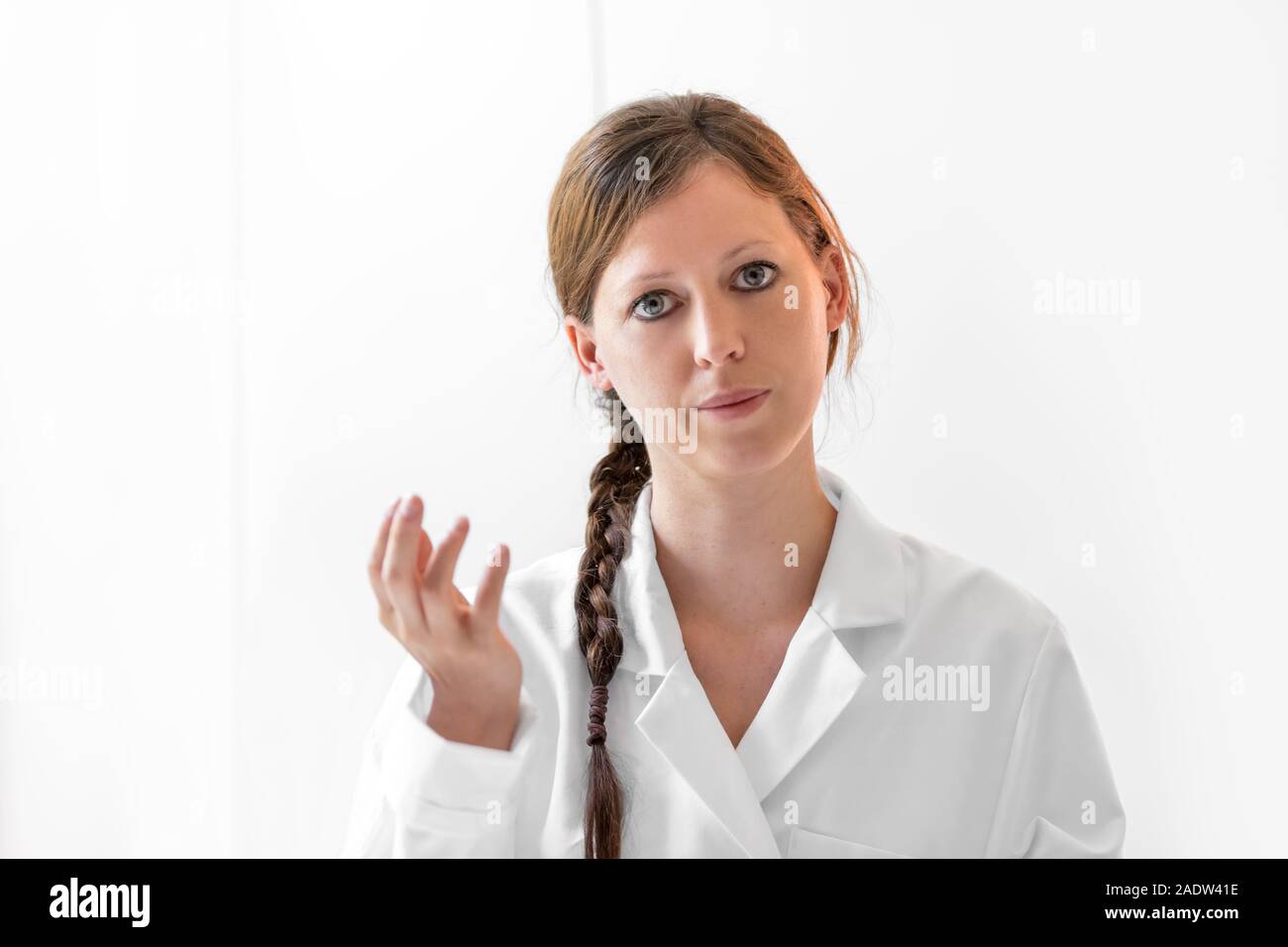 Junge Ärztin in die Kamera schaut, frontale Porträt einer ernst Professional, weißer Hintergrund Stockfoto