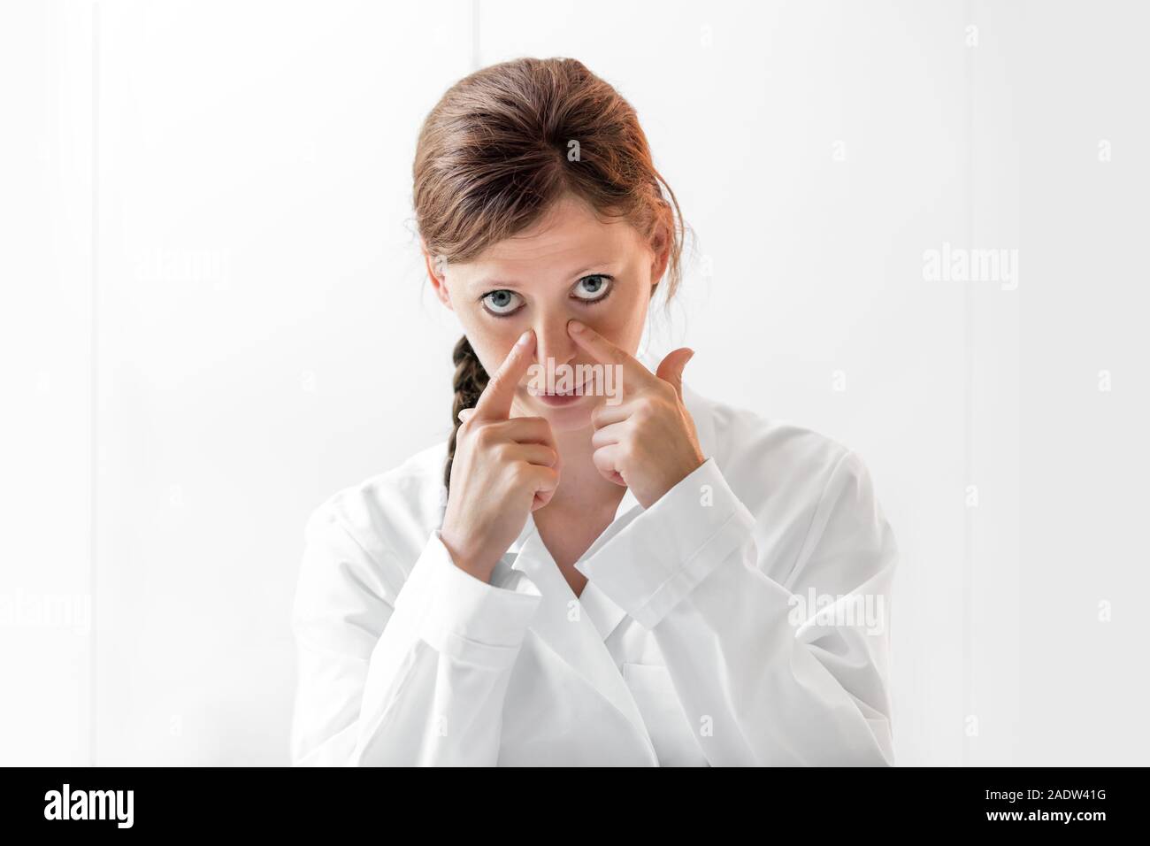 Junge Ärztin zeigen, wie Nasennebenhöhlen oder der Nase Krankheiten zu prüfen, weisser Hintergrund mit Copyspace Stockfoto