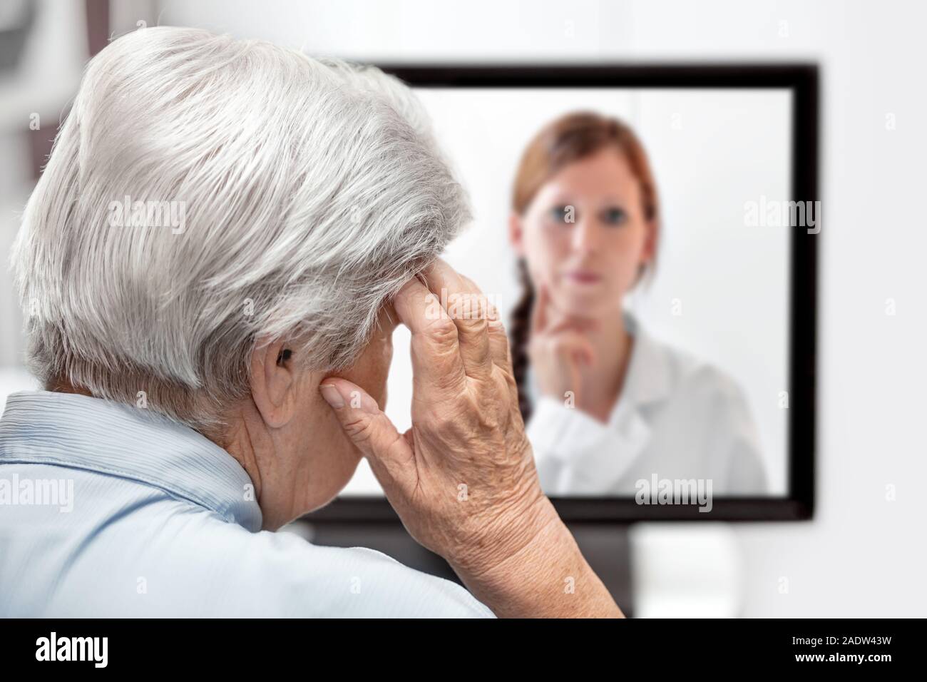 Ältere Frau mit Kopfschmerzen, Arzt auf dem Monitor hören, Konzept Telemedizin und Konsultation Stockfoto