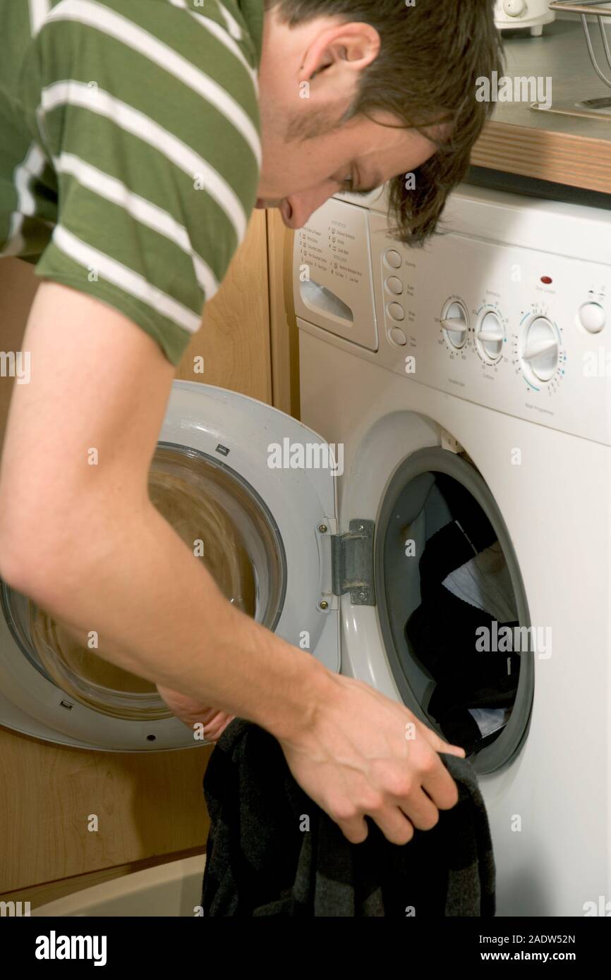Junger Mann die Wäsche in der Waschmaschine, Nahaufnahme, Seite, Ansicht Stockfoto