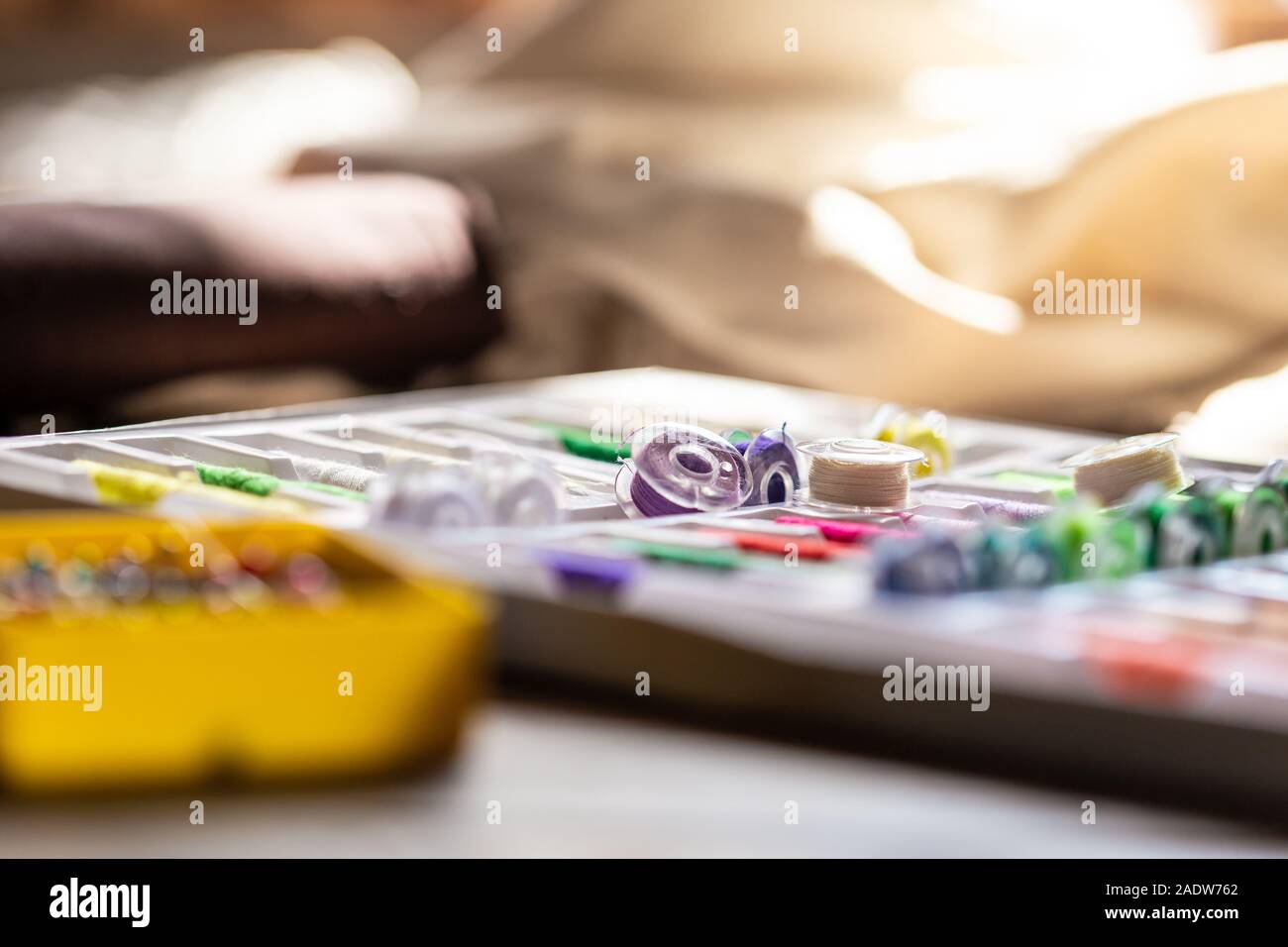 Menge Nähtechnik auf einem Holztisch, Nähmaschine im Hintergrund Stockfoto