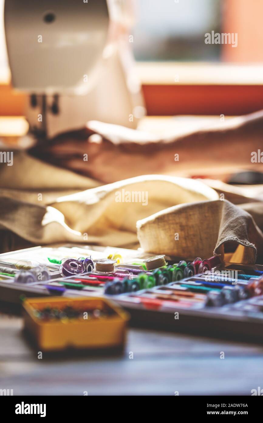 Menge Nähtechnik auf einem Holztisch, Nähmaschine im Hintergrund Stockfoto