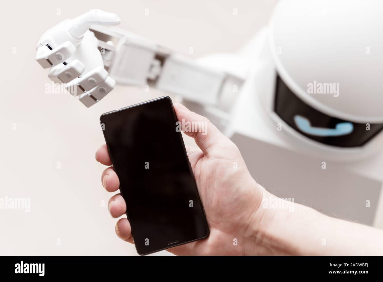 Service Roboter erreicht ein Smartphone zu einem Mann mit einem Telefonsymbol auf seinem Display Stockfoto