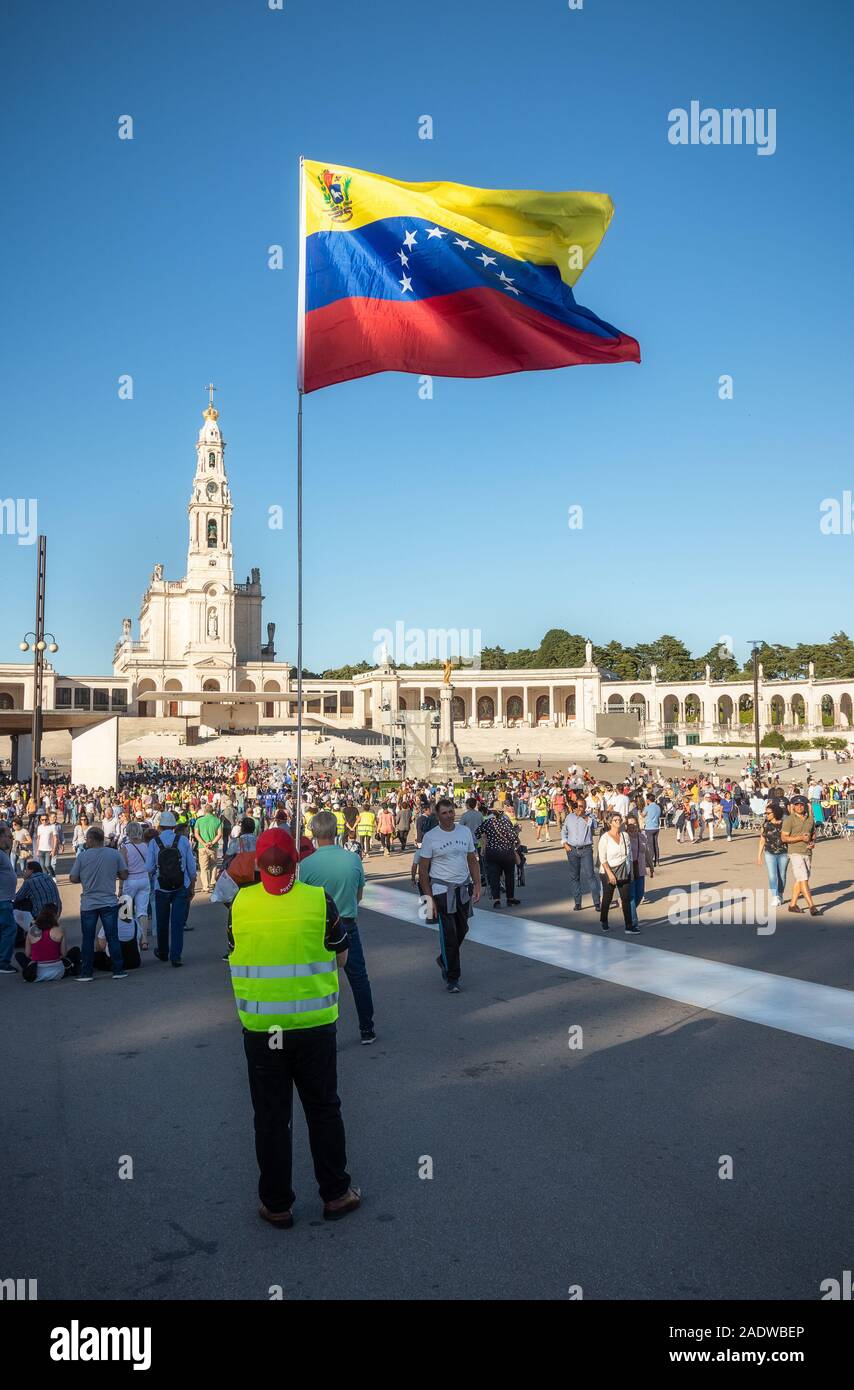 Fatima, Portugal - 12. Mai 2019: Pilgrim mit Flagge Venezuela im Heiligtum von Fatima, Portugal flattern, mit der Basilika im Hintergrund. Stockfoto