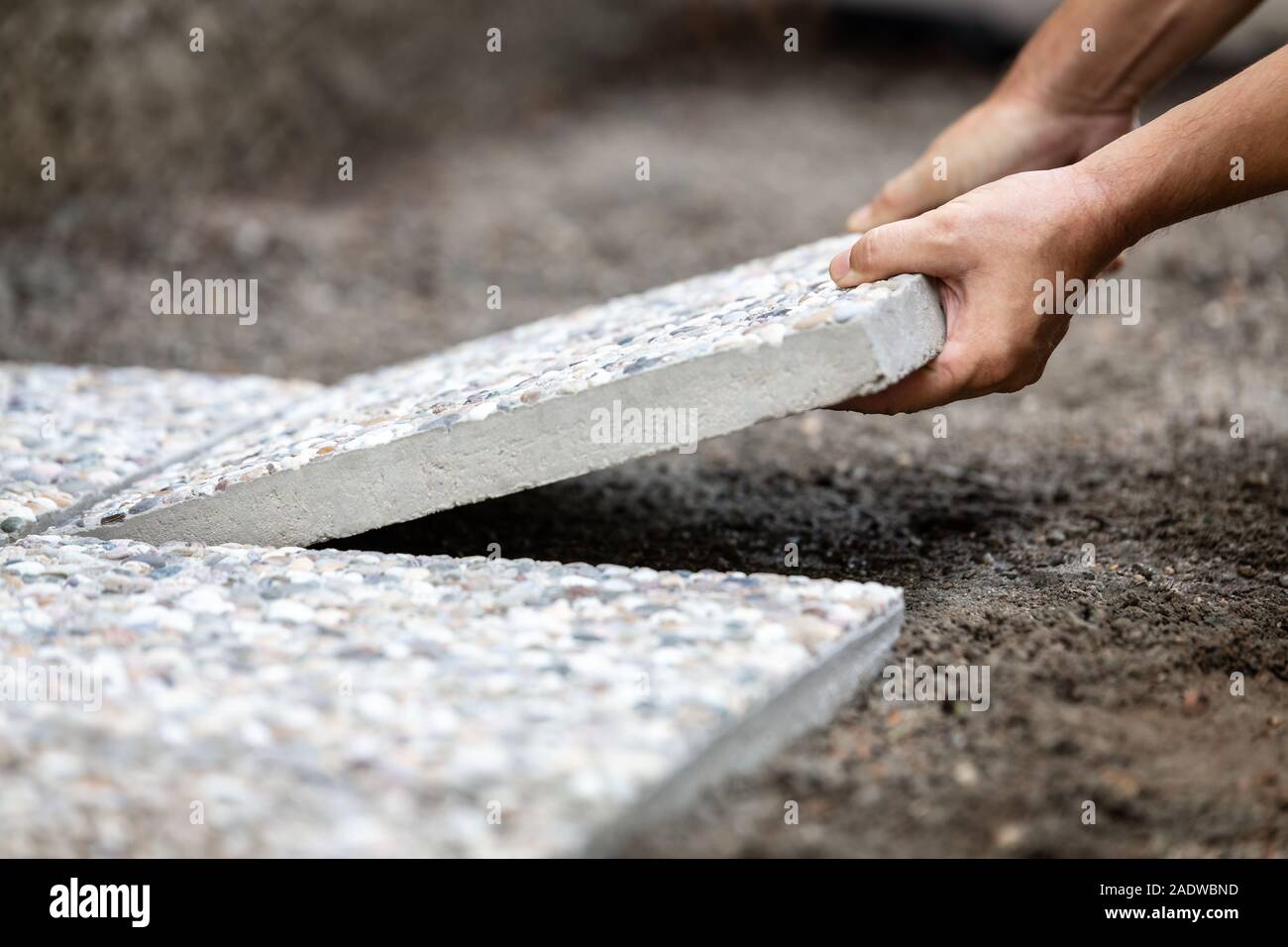 Der Mensch bewegt sich gewaschen Betonplatten in ein Kiesbett, frisch gelegte Weg aus Betonplatten im Außenbereich Stockfoto