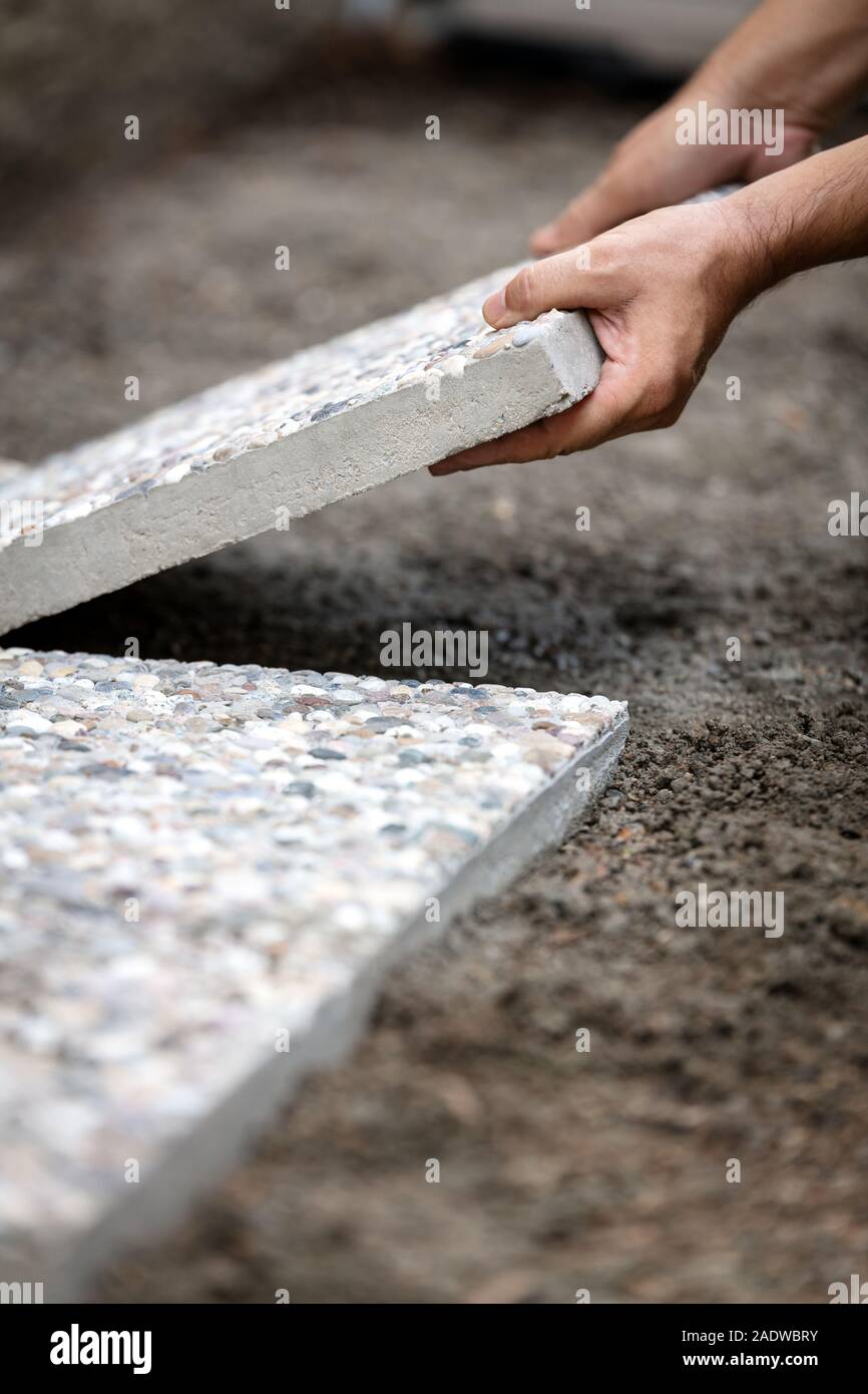 Der Mensch bewegt sich gewaschen Betonplatten in ein Kiesbett, frisch gelegte Weg aus Betonplatten im Außenbereich Stockfoto