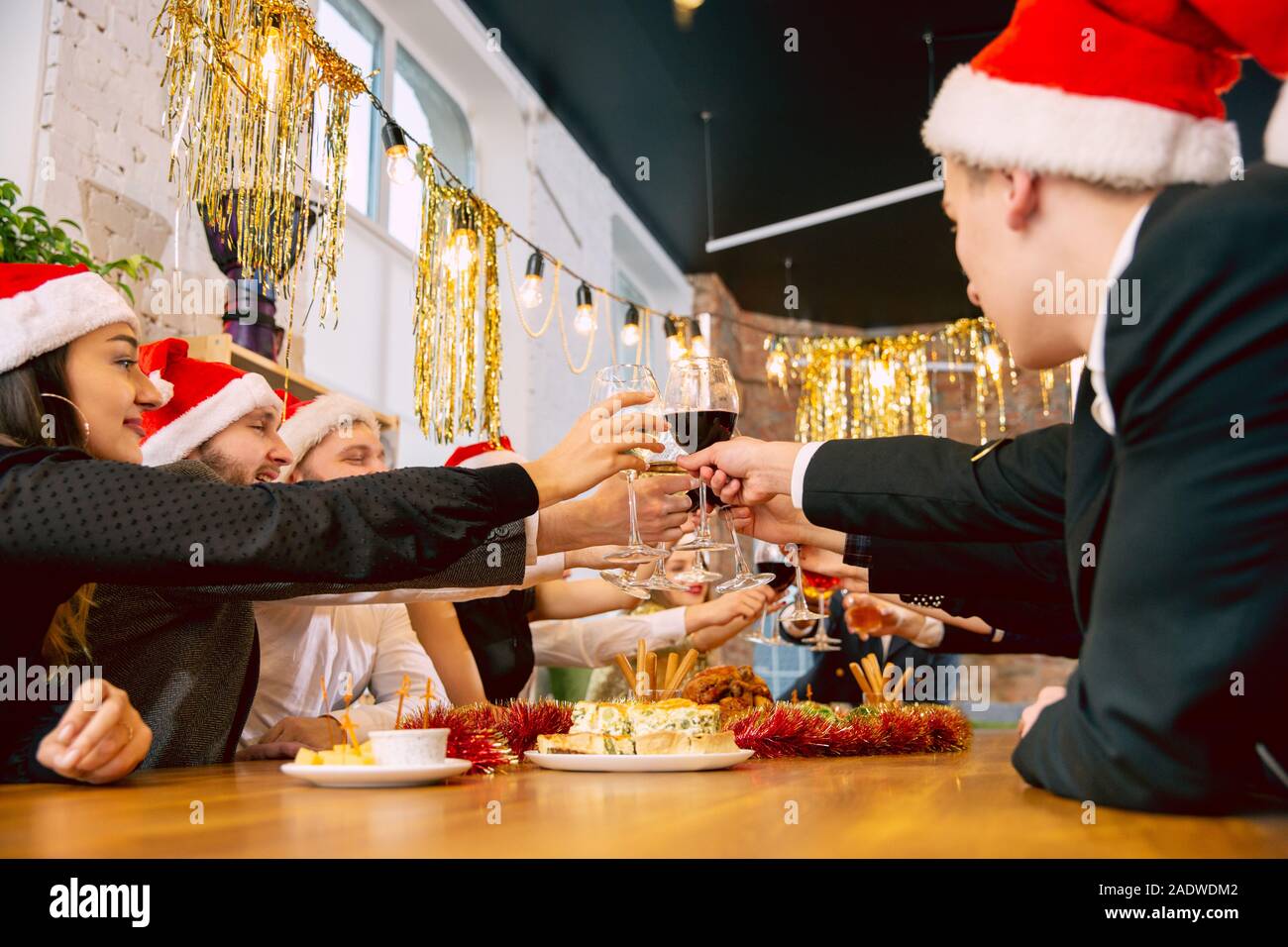 Glückliche Mitarbeiter feiern, während Unternehmen neues Jahr und Weihnachtsfeier. Junge kaukasier, in Feiern, Kleidung, Wein trinken, Prost. Konzept der Office Kultur, Teamarbeit, Freundschaft, Winter. Stockfoto