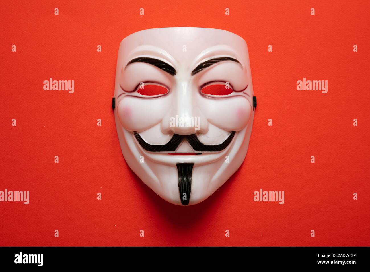 Vendetta Maske Symbol für anonyme online acktivist Gruppe gegen rot-orange Farbe Hintergrund, Detailansicht. Stockfoto