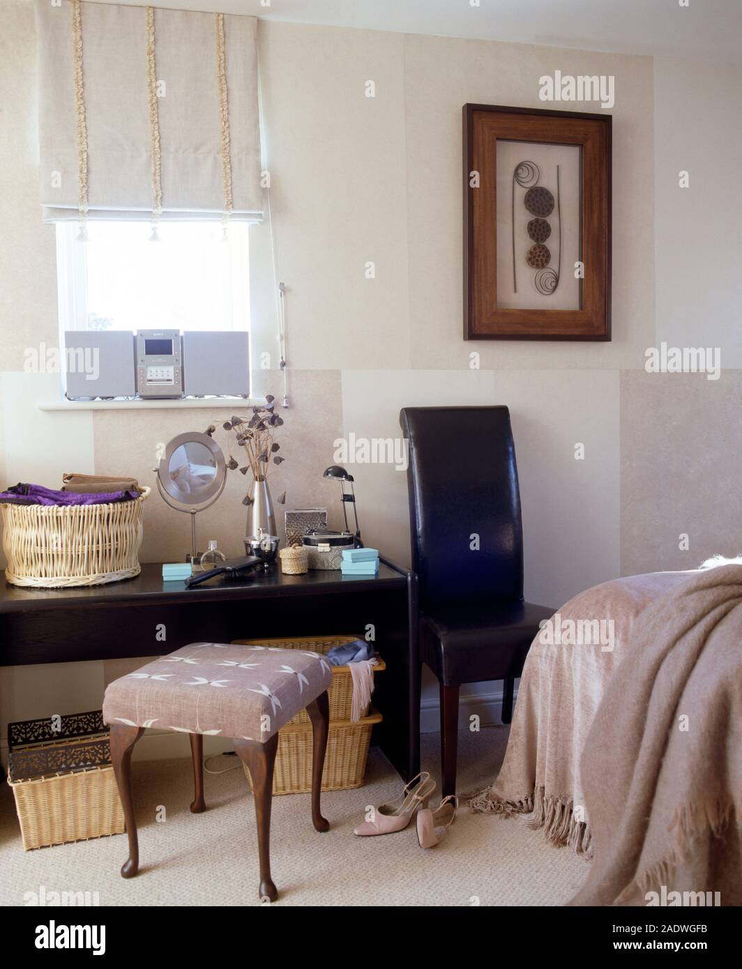 Hocker bei Schminktisch unter schmales Fenster mit einer Creme Bettwäsche blind in ein modernes Schlafzimmer mit einem Leder Stuhl gepolstert Stockfoto