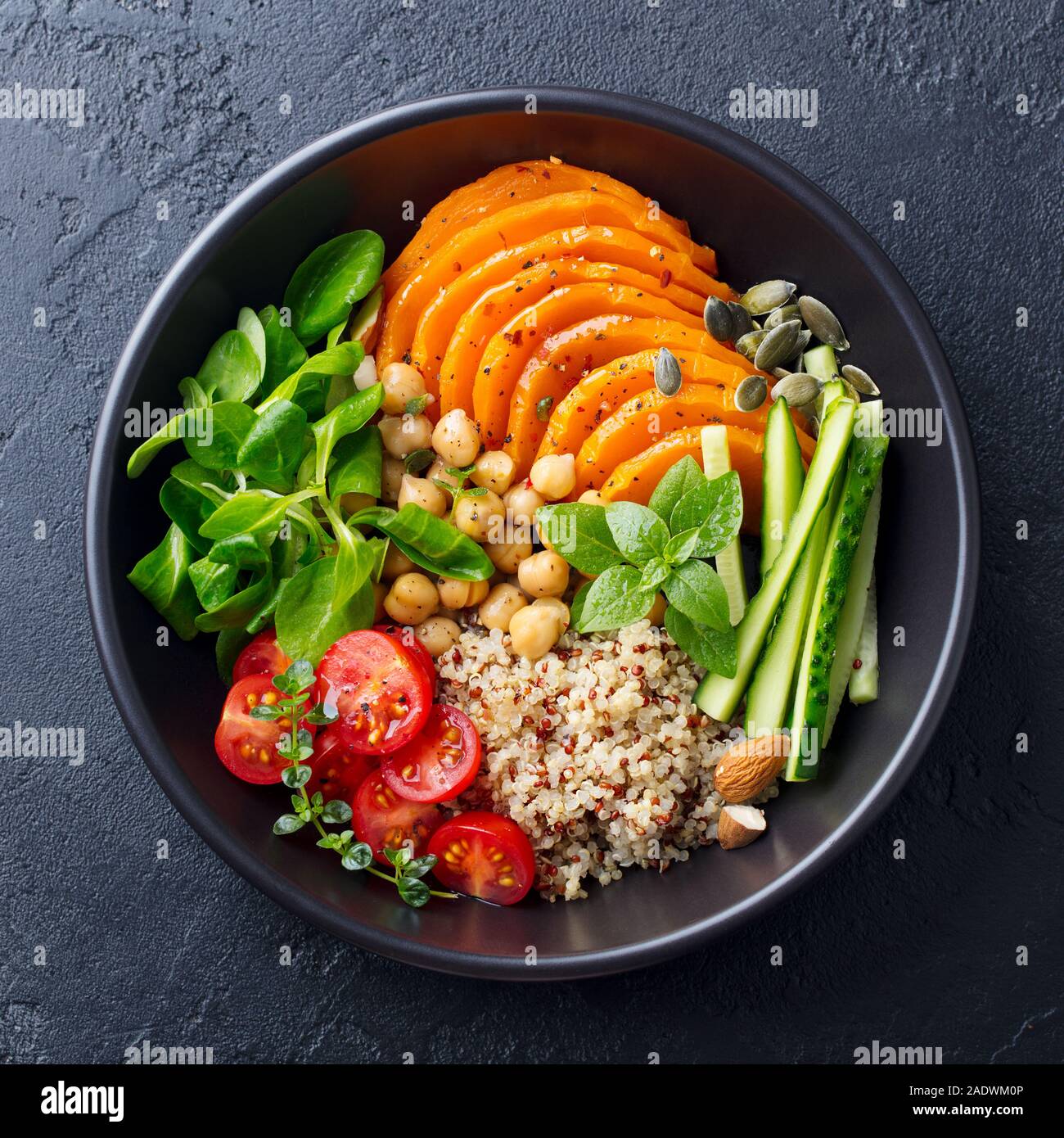 Gesunde vegetarische Salat. Gebratener Kürbis, Quinoa, Tomaten, grüner Salat. Buddha Schüssel. Schiefer Hintergrund. Ansicht von oben. Stockfoto