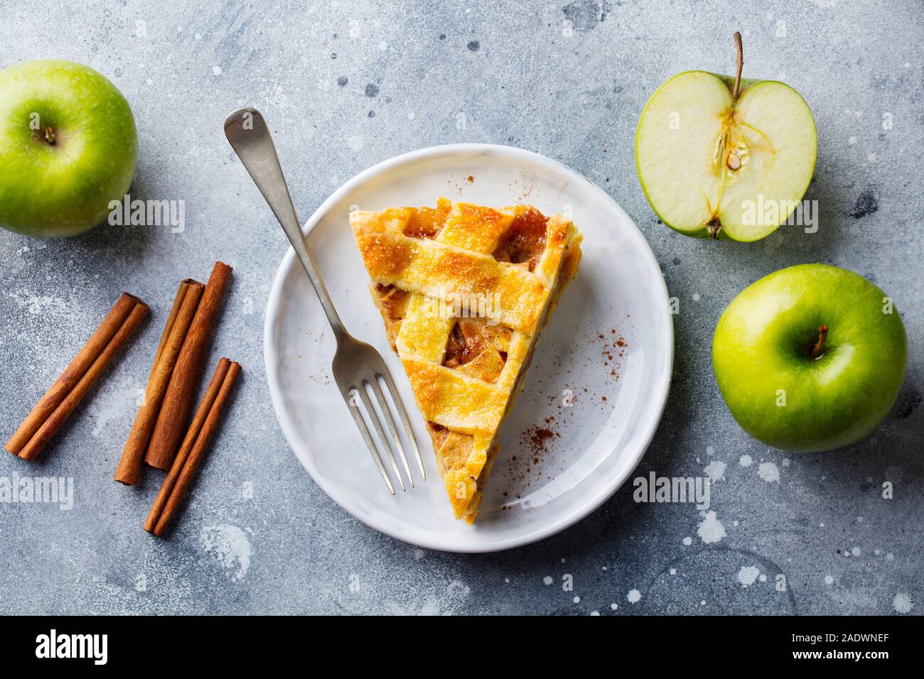 Apfelkuchen mit Karamell auf einem weißen Teller. Grauer Hintergrund. Ansicht von oben Stockfoto