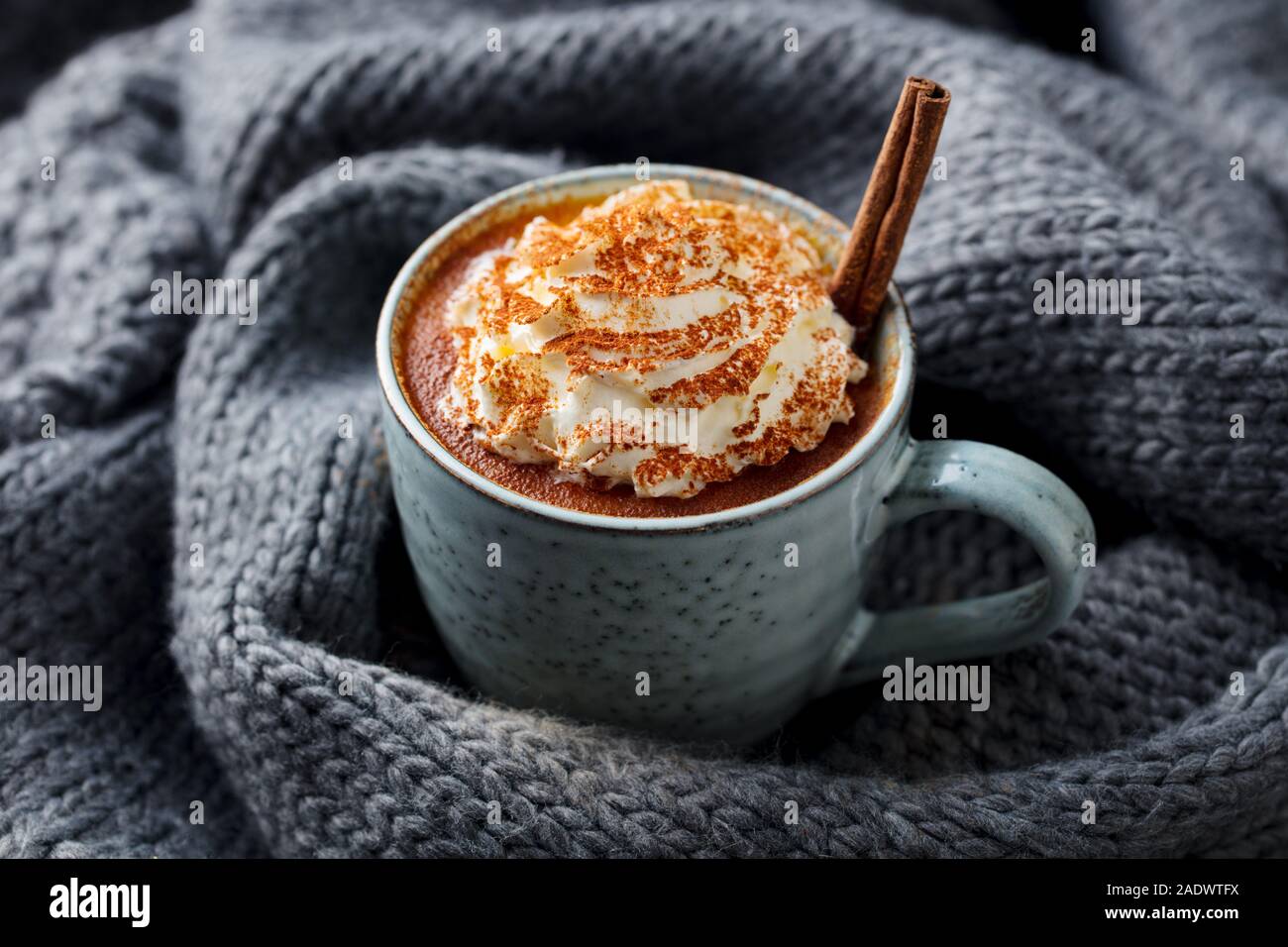 Kürbis Latte mit Gewürzen Schlagsahne. Grau gestrickt Hintergrund Stockfoto