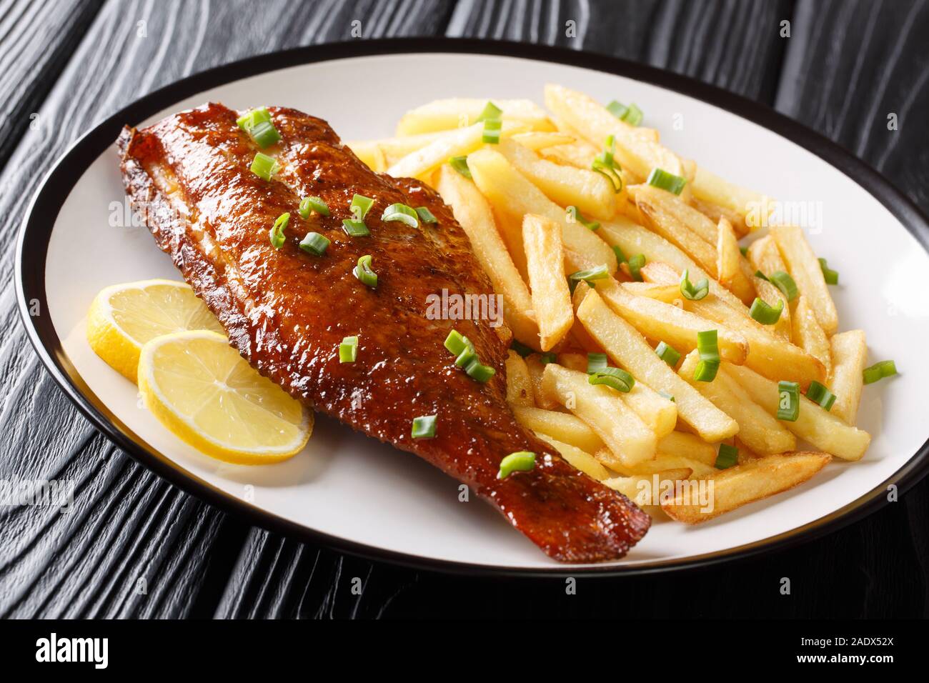 Gebackene Zackenbarsch Fisch mit Pommes Frites und Zitronensaft close-up in einem Teller auf dem Tisch. Horizontale Stockfoto