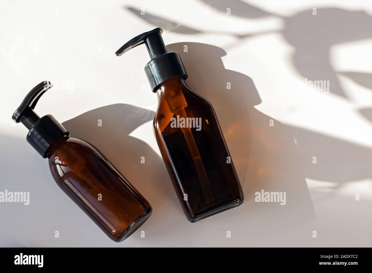 Zwei Glasflaschen mit natürliche Körper- und Haarpflege Kosmetik auf weißem Tabelle, Ansicht von oben. Stockfoto