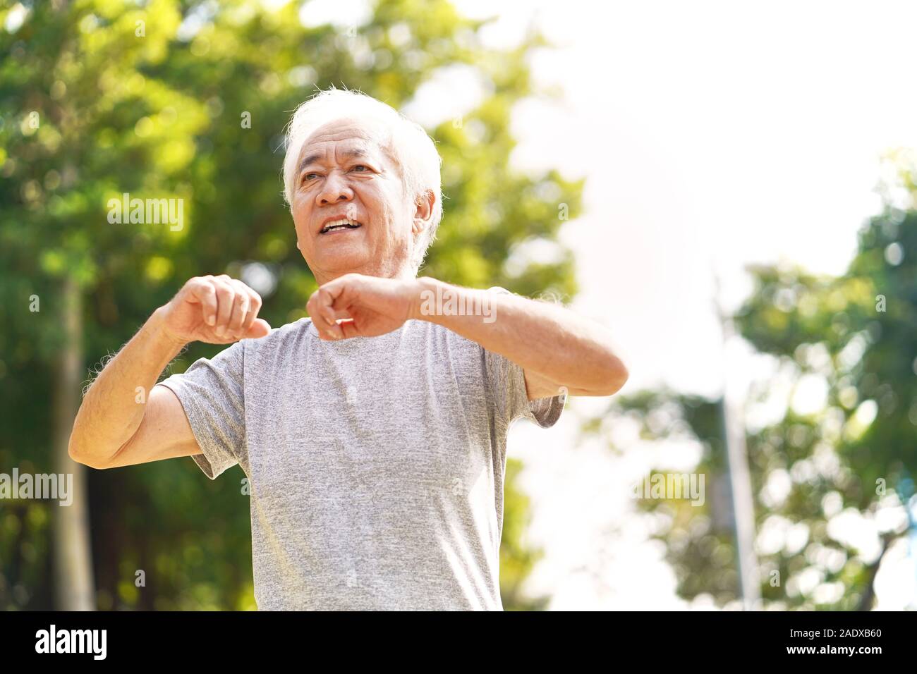 Gesunde ältere asiatischer Mann zu Fuß trainieren stretching Arms im Freien Stockfoto