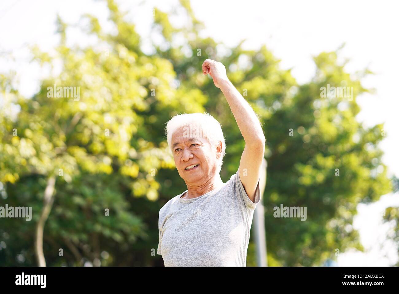 Gesunde ältere asiatischer Mann zu Fuß trainieren stretching Arms im Freien Stockfoto