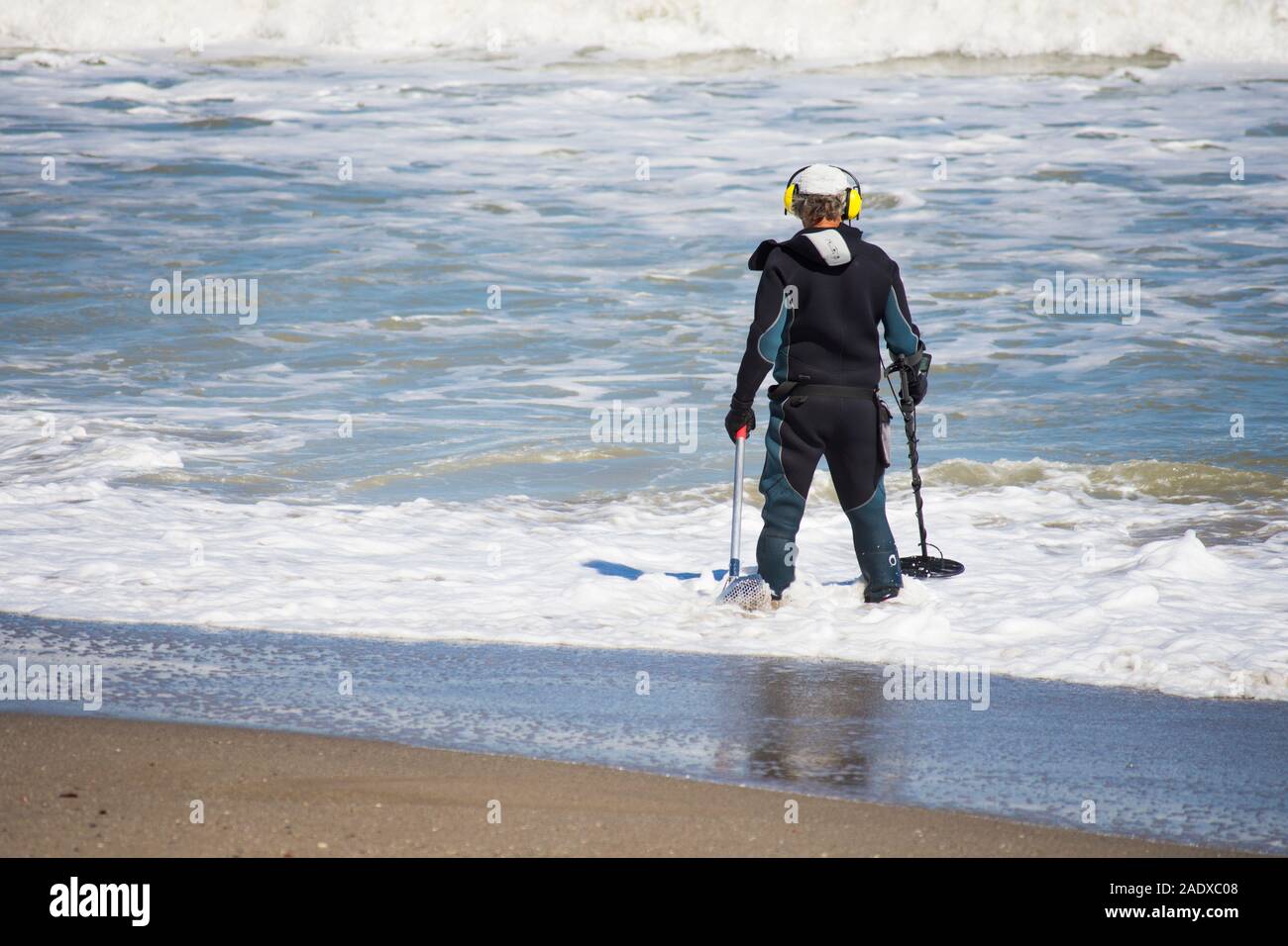 Mann im Anzug am Strand mit Metalldetektor, Spanien suchen. Stockfoto