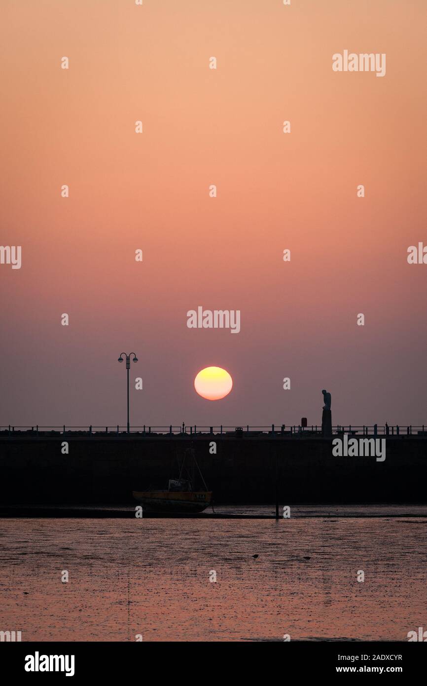 Sonnenuntergang in der Bucht von Morecambe, Lancashire, UK. Ein Blick über den Sandstrand von Morecambe Bay wie die Sonne über den steinernen Steg am Ende des Tages setzt. Stockfoto