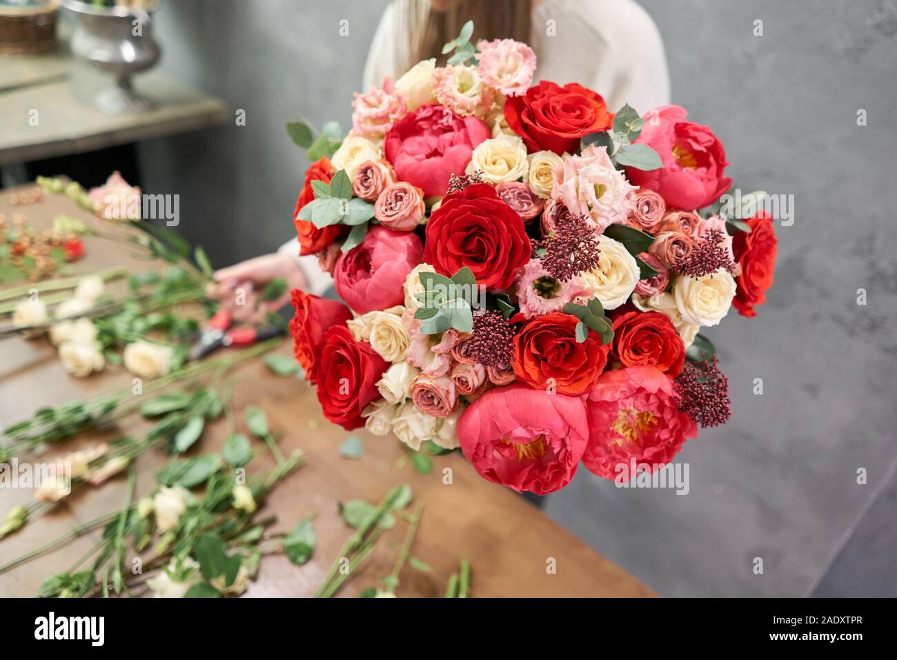 Europäische floral Shop Konzept. Floristin Frau schafft Red schöner Blumenstrauß aus gemischten Blumen. Schönen frischen Haufen. Bildung, master class und Stockfoto
