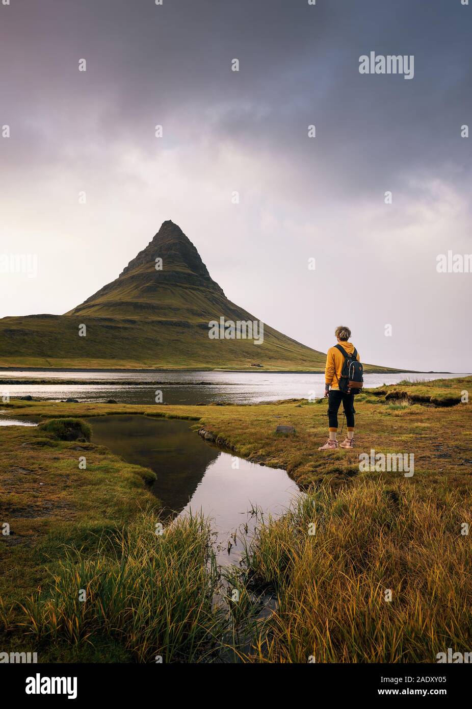 Junge Wanderer mit Rucksack schaut die Kirkjufell Berg Islands. Dieser 463 m hohe Berg liegt an der Nordküste Islands Snæfells entfernt Stockfoto