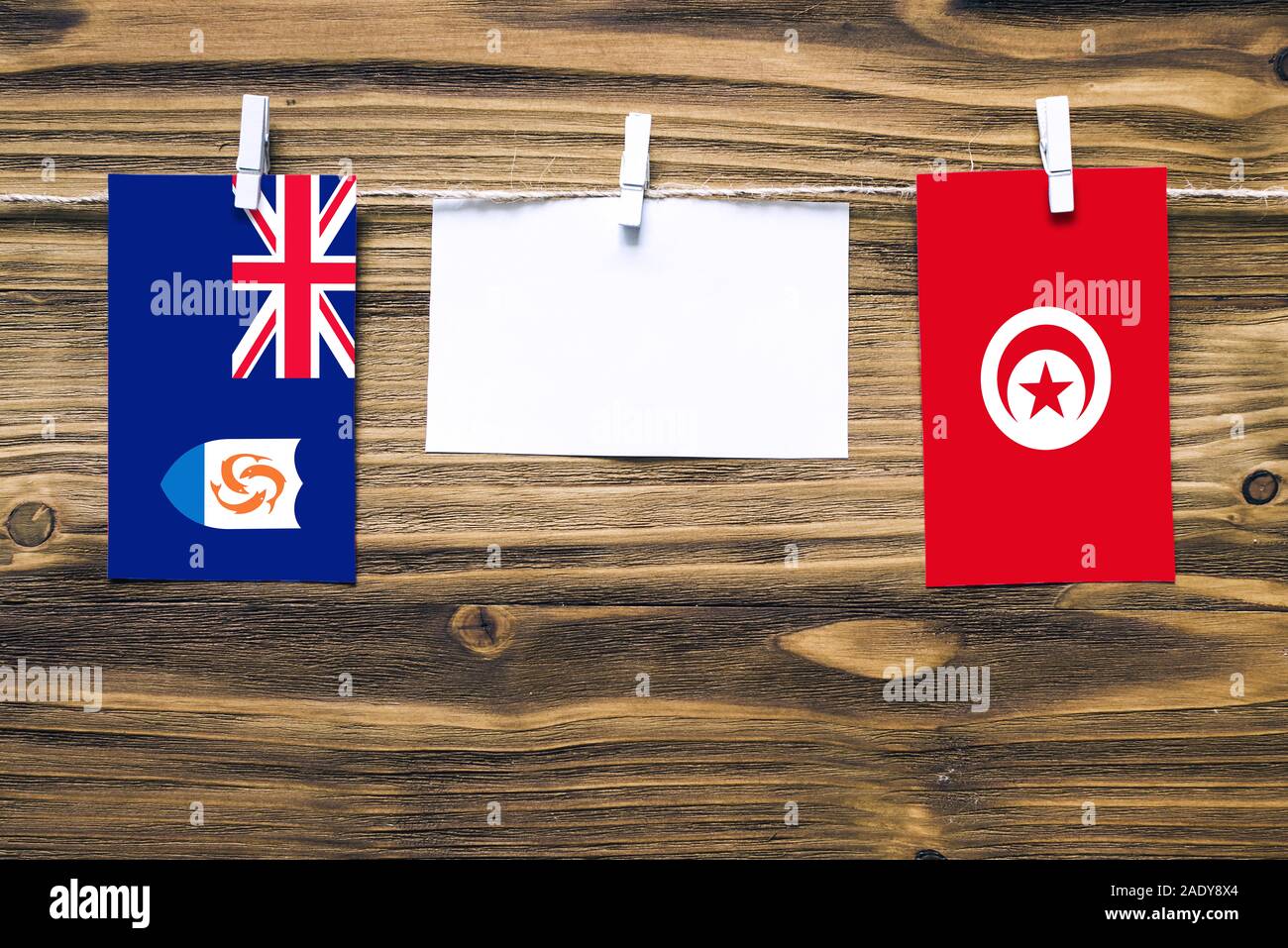 Hängenden Flaggen von Anguilla und Tunesien, Seil mit wäscheklammer mit Kopie Raum befestigt auf weißem Papier auf Holz- Hintergrund. Diplomatische Beziehungen Stockfoto
