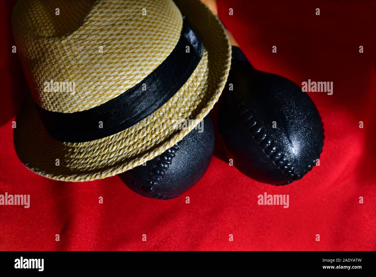 Typische kubanische Hut mit schwarzem Band neben Maracas auf einem roten Hintergrund. Stockfoto