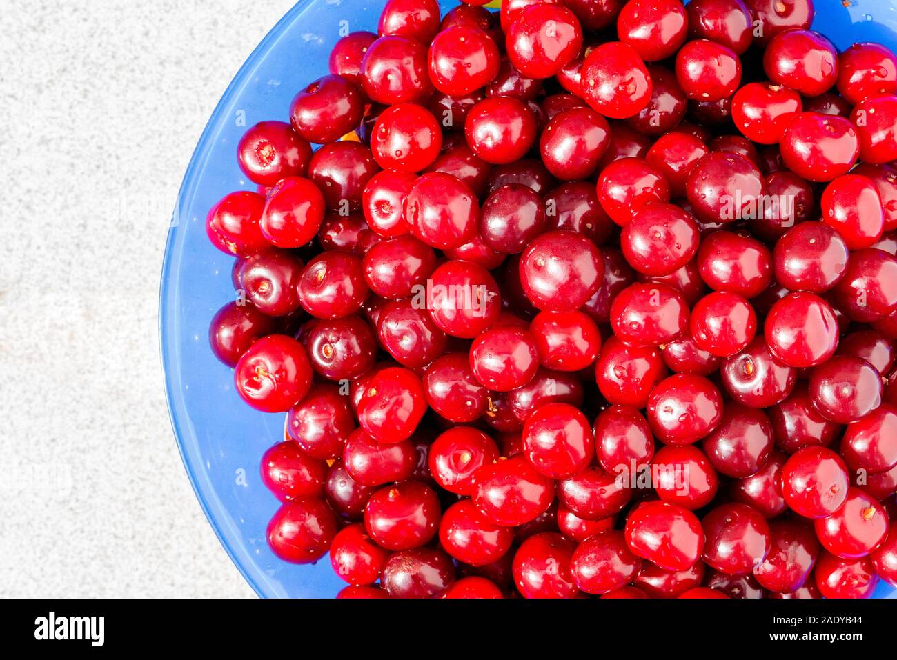 Ein großer Haufen von Kirschen mit Stiel entfernt auf einem Teller stapelten, Schuß Form oben. Stockfoto