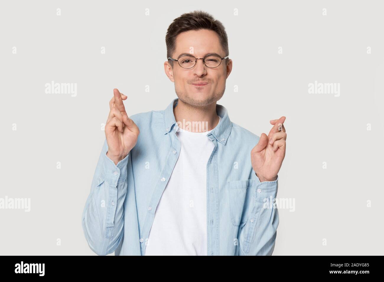 Sicher schöner Mann im Hemd kreuz Fingern beten für Glück Stockfoto