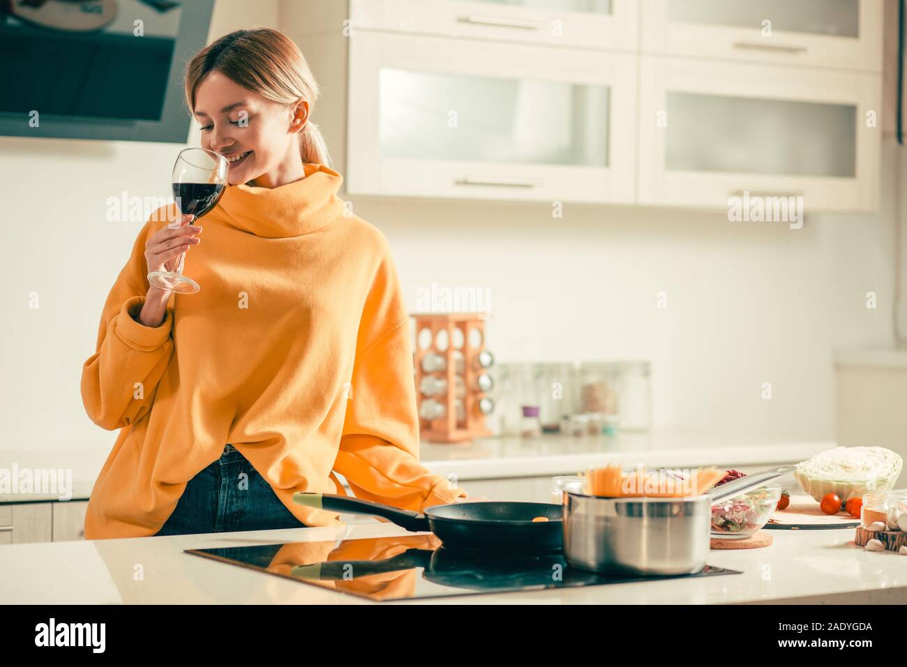 Glückliche junge Dame das Trinken von Wein in der Küche und lächelnd Stockfoto