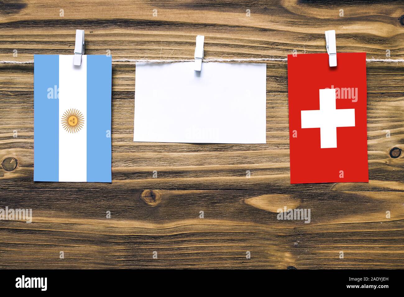 Hängenden Flaggen von Argentinien und der Schweiz Seil mit wäscheklammer mit Kopie Raum befestigt auf weißem Papier auf Holz- Hintergrund. Diplomatische Beziehungen Stockfoto